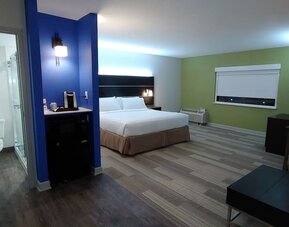 Spacious guest room featuring a king bed, a kitchenette area, a walk-in shower, and an open-concept layout at Holiday Inn Express Rolling Meadows-Schaumburg.