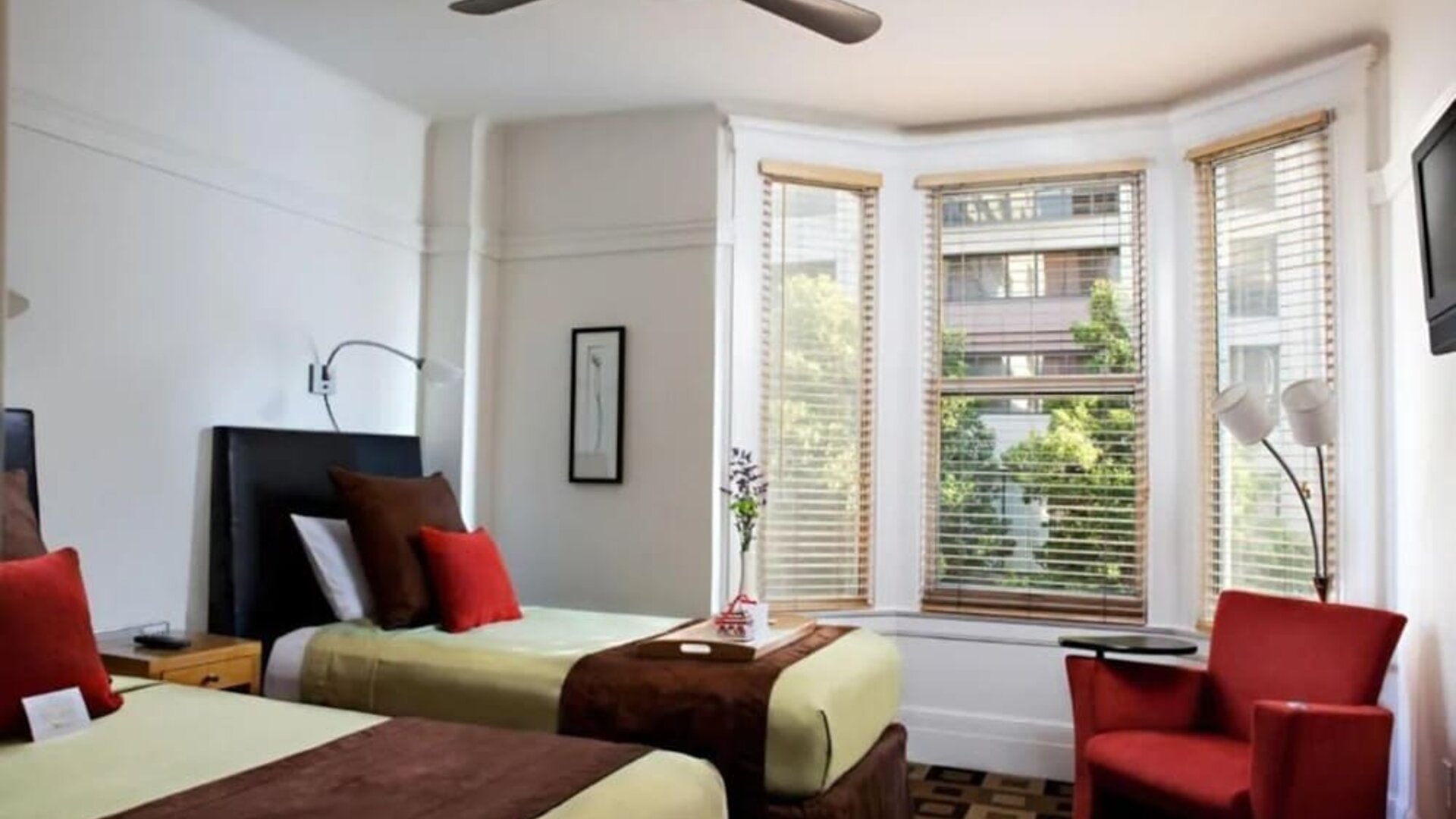 Guest room featuring two beds, a bay window, comfortable seating, and abundant natural light at The Mosser Hotel.