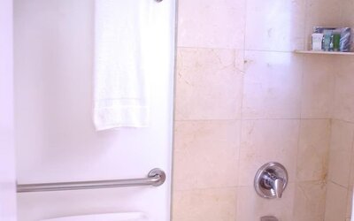 Bathroom featuring a combination bathtub and shower, stone tile walls, chrome fixtures, and neatly arranged towels at The Mosser Hotel.