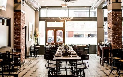 Restaurant featuring exposed brick walls, communal dining tables, high ceilings, and an industrial-inspired design at The Mosser Hotel.