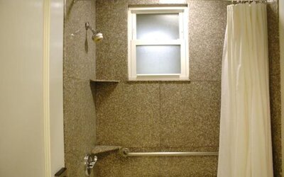 Bathroom featuring a walk-in shower, granite-style wall finishes, accessibility features, and natural light at The Mosser Hotel.