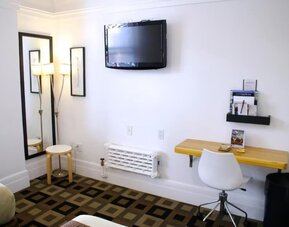 Guest room workspace featuring a wall-mounted television, a compact desk, modern seating, and a dedicated work area at The Mosser Hotel.