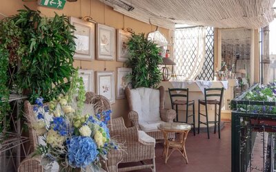 Outdoor patio featuring wicker seating, lush greenery, floral arrangements, and a relaxed terrace atmosphere at Cellai Boutique Hotel.
