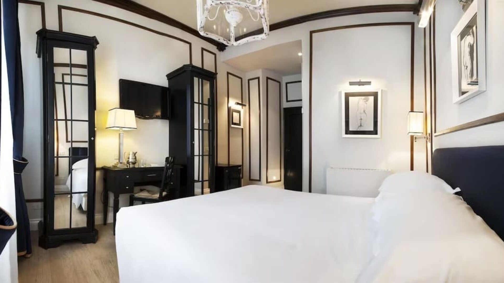 Spacious room featuring a large bed, decorative wall molding, mirrored wardrobes, and sophisticated furnishings at Cellai Boutique Hotel.