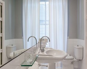 Bathroom featuring a pedestal sink, oversized mirror, bright natural light, and classic European design at Cellai Boutique Hotel.