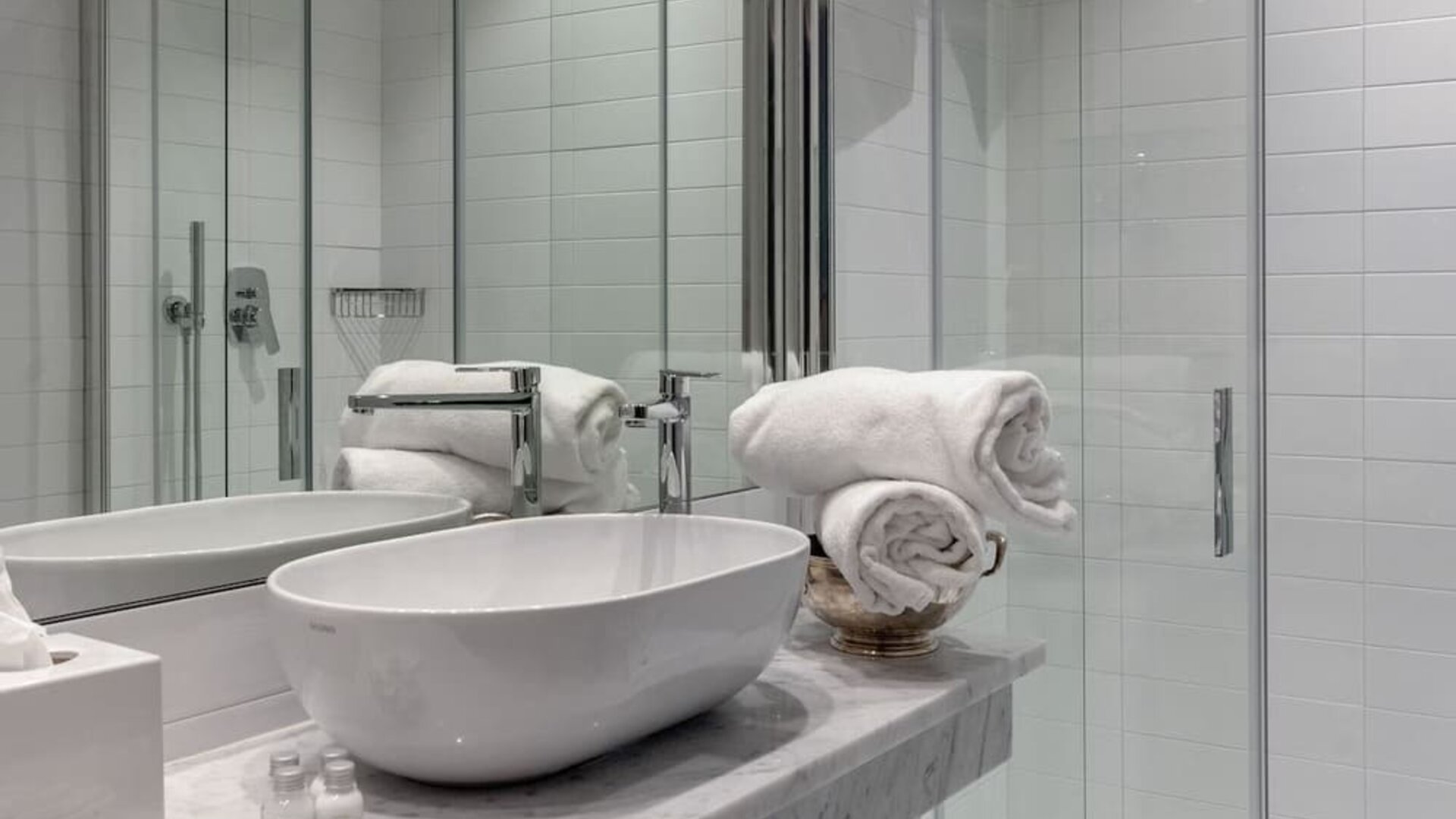 Bathroom featuring a marble vanity, vessel sink, glass-enclosed shower, and modern fixtures at Cellai Boutique Hotel.