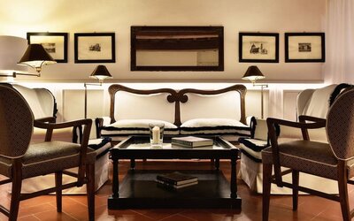 Seating area featuring upholstered chairs, warm lighting, framed artwork, and a classic lounge setting at Cellai Boutique Hotel.