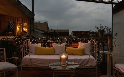Outdoor patio featuring cushioned seating, candlelight, decorative string lights, and rooftop views at Cellai Boutique Hotel.