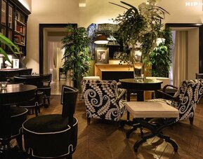 Lobby area featuring decorative floral arrangements, library-style shelving, patterned seating, and an intimate atmosphere at Cellai Boutique Hotel.