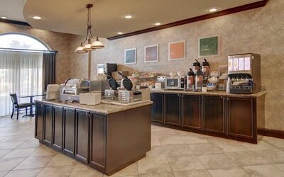 Complimentary breakfast area featuring hot breakfast stations, cereal dispensers, coffee service, and self-serve dining options at Comfort Suites Frisco.