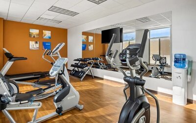 Hotel gym with treadmills, elliptical machines, dumbbells, and mirrored walls at Comfort Suites Frisco.