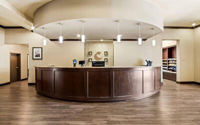 Reception desk with a curved granite counter, pendant lighting, and a convenient snack market at Comfort Suites Frisco.