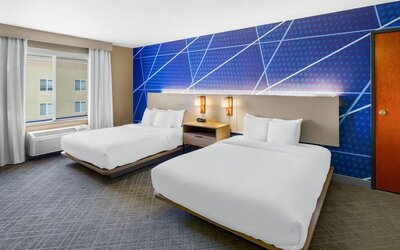 Guest room featuring two queen beds, modern blue accent décor, bedside lighting, and a large window at Comfort Suites Vacaville-Napa Valley Area.