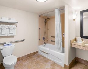 Accessible bathroom with a bathtub and shower combination, grab bars, spacious vanity, and fresh towels at Comfort Suites Vacaville-Napa Valley Area.
