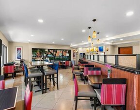 Bright dining and breakfast area with a variety of tables, comfortable seating, and large windows at Comfort Suites Vacaville-Napa Valley Area.