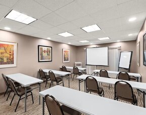 Meeting room arranged with tables and chairs, a projection screen, and presentation equipment at Comfort Suites Vacaville-Napa Valley Area.