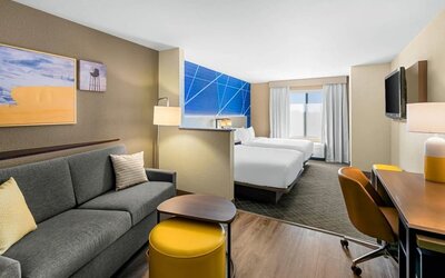 Spacious suite with two beds, a separate sitting area, sofa, workspace, and flat-screen television at Comfort Suites Vacaville-Napa Valley Area.