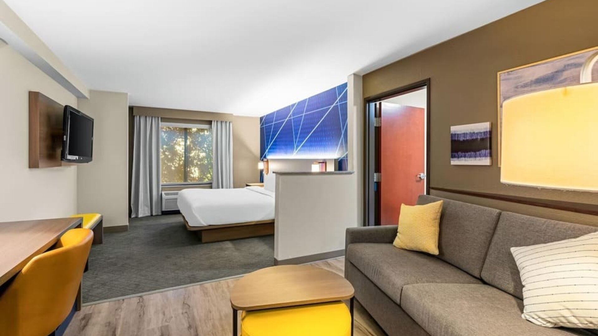 Bright suite featuring a separate living area with a sofa and workspace alongside the sleeping area at Comfort Suites Vacaville-Napa Valley Area.