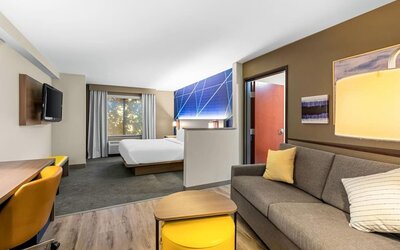 Bright suite featuring a separate living area with a sofa and workspace alongside the sleeping area at Comfort Suites Vacaville-Napa Valley Area.