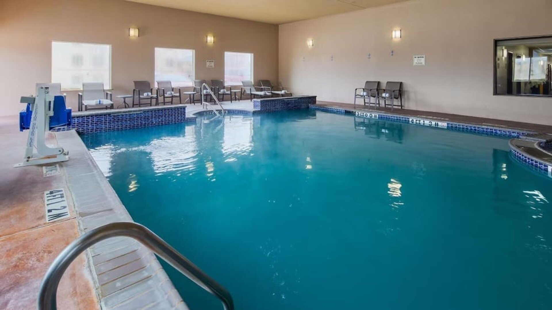 Indoor swimming pool featuring lounge seating and an accessible pool lift at Best Western Granbury Inn & Suites.
