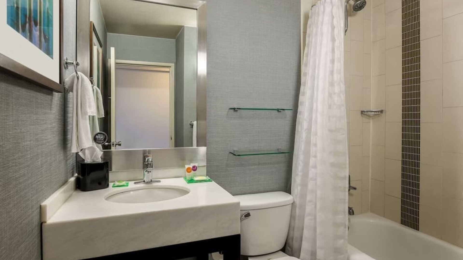 Guest bathroom featuring a modern vanity, large mirror, toilet, and bathtub with shower at Hyatt Place San Jose Downtown.