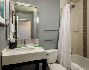Guest bathroom featuring a modern vanity, large mirror, toilet, and bathtub with shower at Hyatt Place San Jose Downtown.