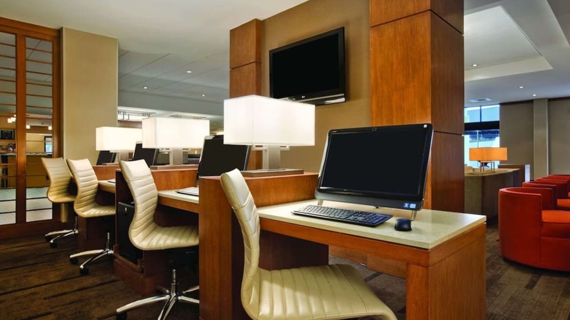Business centre featuring multiple computer workstations, desk chairs, and individual task lighting at Hyatt Place San Jose Downtown.