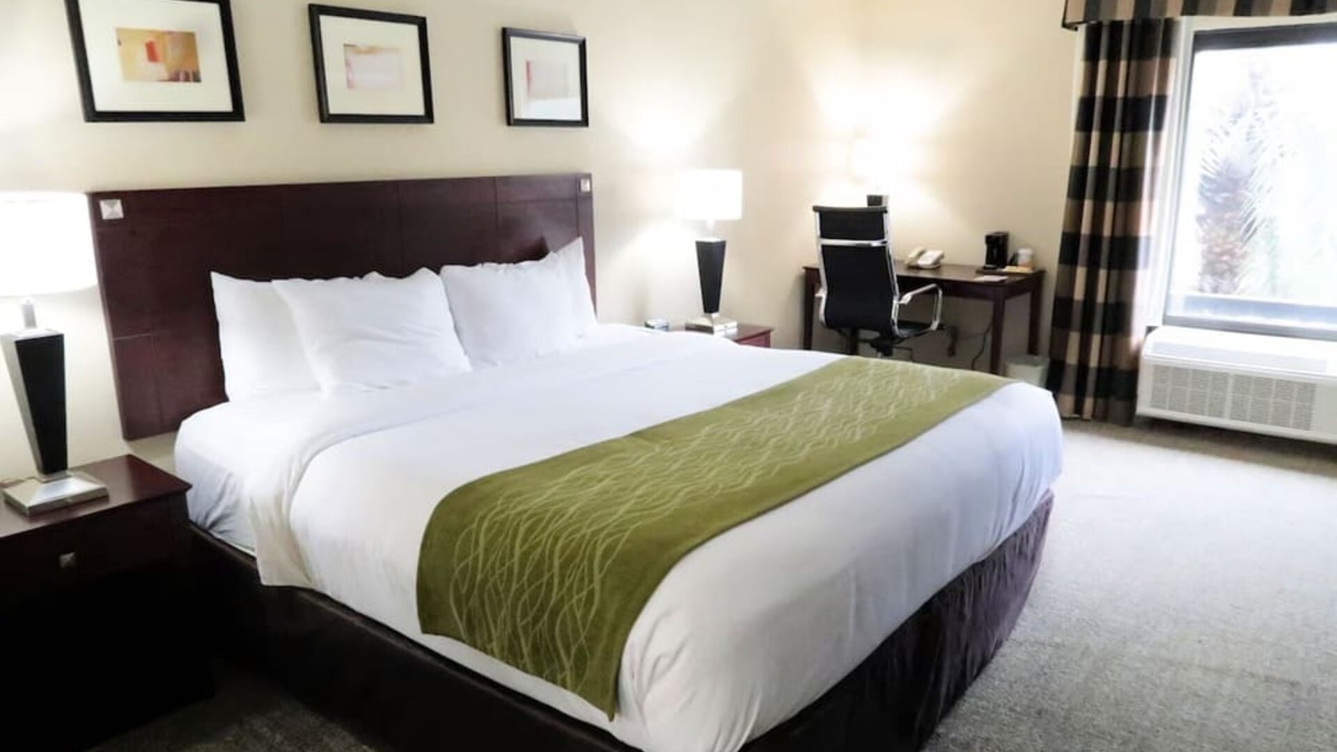 Bright king guest room featuring a king bed, work desk, chair, bedside lighting, and large window providing natural light at Comfort Inn Southwest At Westpark.