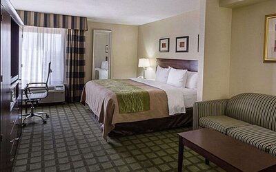 Spacious guest room featuring a king bed, sofa seating area, coffee table, workspace, and large window at Comfort Inn Southwest At Westpark.