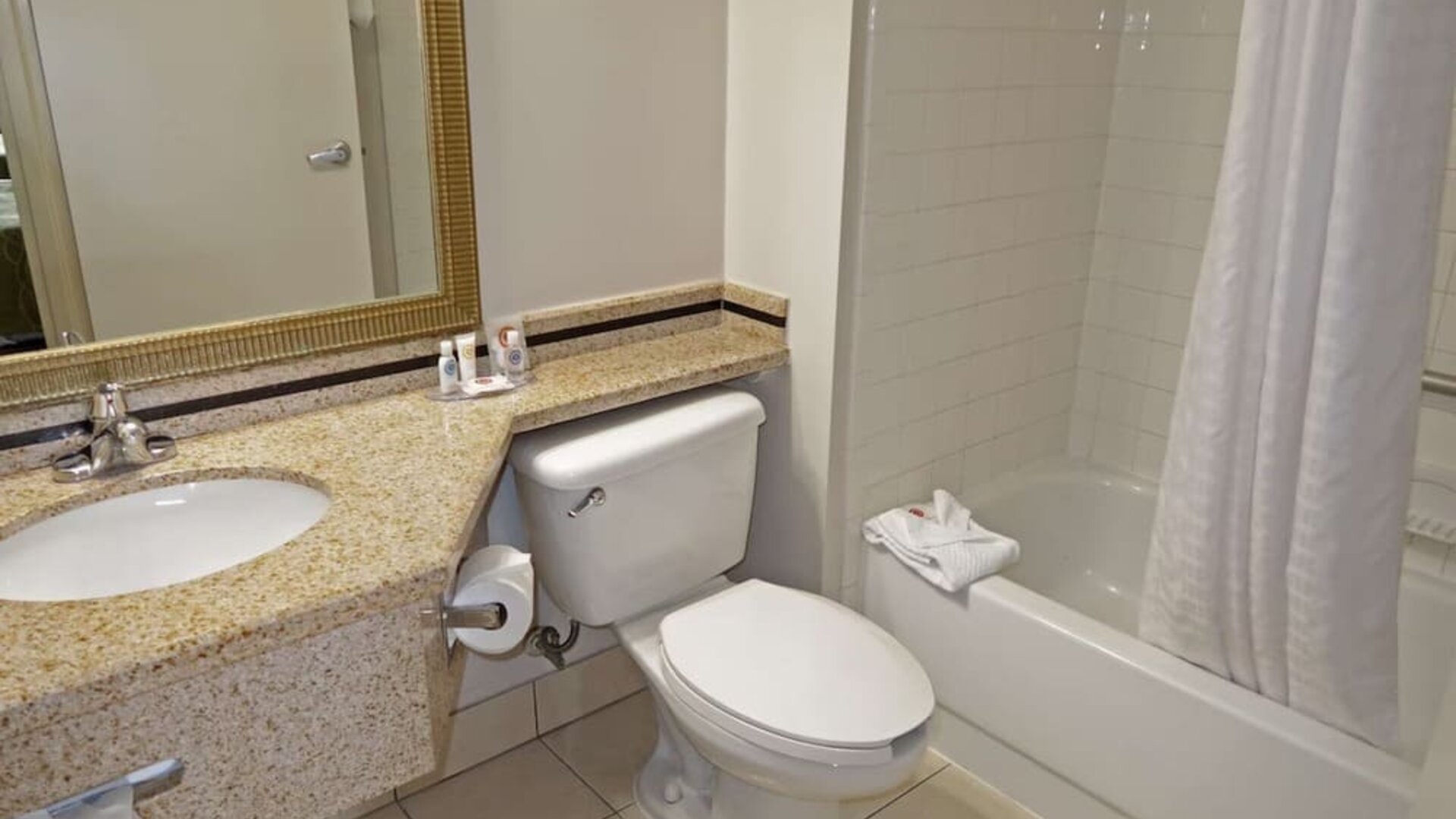 Guest bathroom featuring a granite vanity, large mirror, toilet, and bathtub with shower at Comfort Inn Southwest At Westpark.