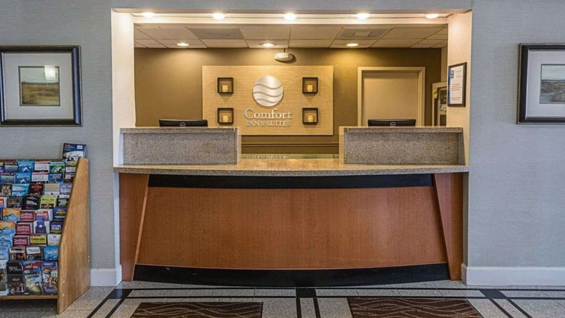 Reception area featuring a front desk, hotel signage, framed artwork, and guest information displays at Comfort Inn Southwest At Westpark.