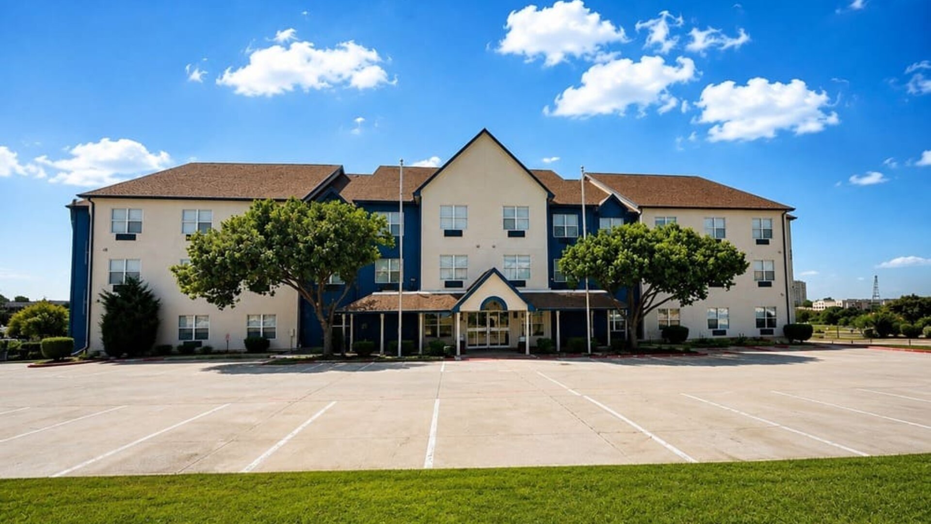 Exterior view of the hotel building, entrance, parking area, and landscaped grounds at SureStay by Best Western Lewisville Dallas.
