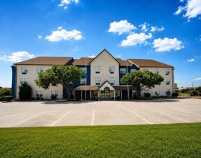 Exterior view of the hotel building, entrance, parking area, and landscaped grounds at SureStay by Best Western Lewisville Dallas.