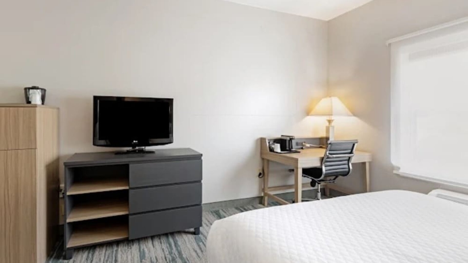Guest room with television, dresser, work desk, office chair, lamp, and large window at SureStay by Best Western Lewisville Dallas.