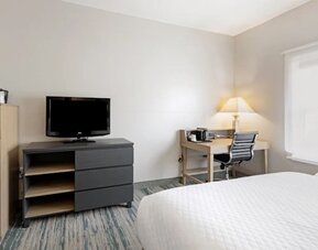 Guest room with television, dresser, work desk, office chair, lamp, and large window at SureStay by Best Western Lewisville Dallas.