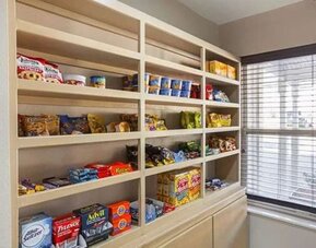 Hotel convenience area with shelves stocked with snacks, drinks, and travel essentials at SureStay by Best Western Lewisville Dallas.