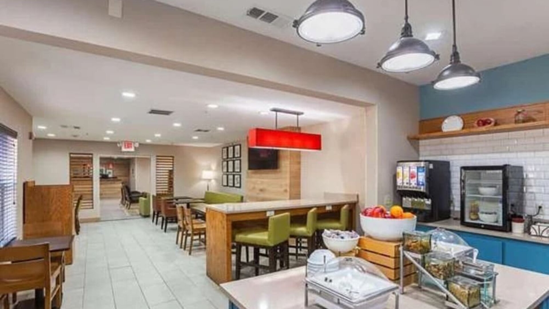 Breakfast and dining area with buffet station, tables, chairs, pendant lighting, and counter seating at SureStay by Best Western Lewisville Dallas.