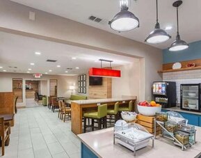 Breakfast and dining area with buffet station, tables, chairs, pendant lighting, and counter seating at SureStay by Best Western Lewisville Dallas.