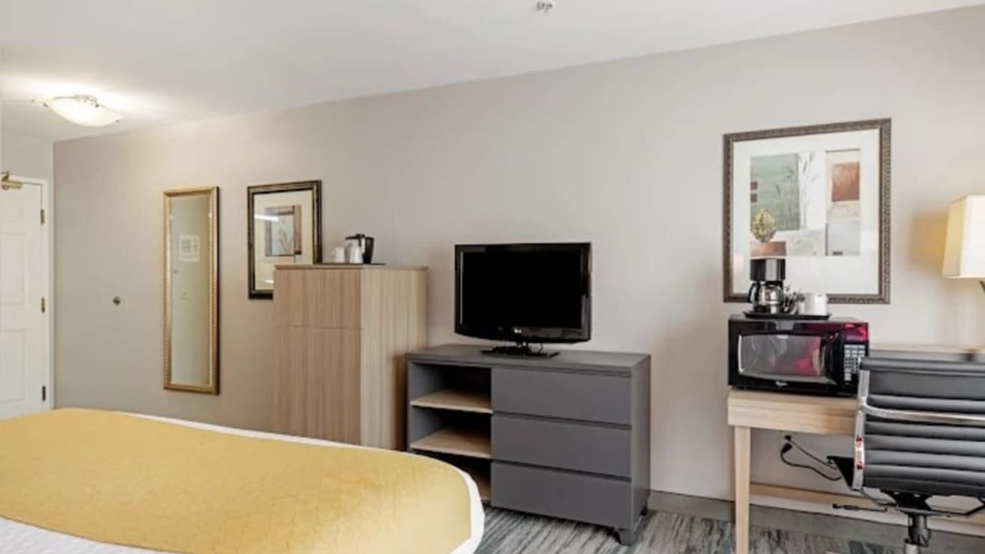 Guest room with television, dresser, microwave, coffee maker, work desk, office chair, and king bed at SureStay by Best Western Lewisville Dallas.