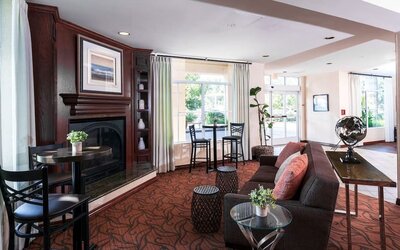Lobby lounge with fireplace, sofa seating, high-top tables, and decorative furnishings at Best Western Ontario Mills Mall.