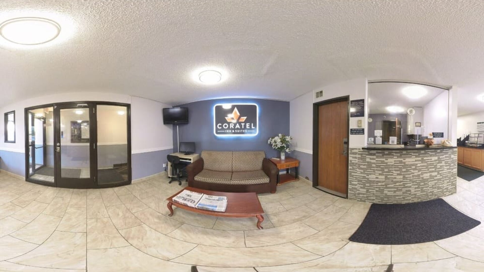 Reception and lobby area with front desk, sofa seating, coffee table, television, and business workstation at Coratel Inn & Suites By Jasper Hastings.