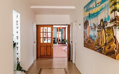 Bright hotel corridor with artwork and wooden doors leading to a common area at Múcura Hotel & Spa.