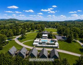 Aerial view of SKYLARANNA Resort & Spa featuring guest buildings, expansive green grounds, swimming pools, and surrounding woodland.