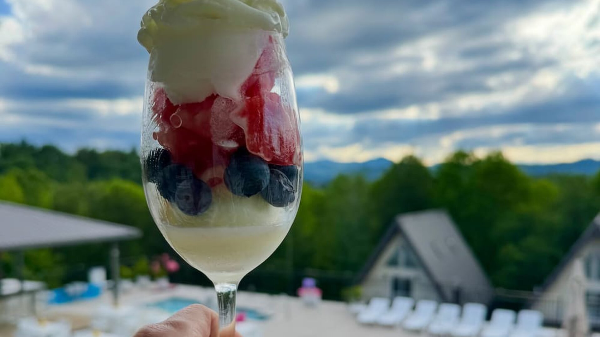 Dessert parfait with berries and whipped cream overlooking the outdoor pool and mountain scenery at SKYLARANNA Resort & Spa.