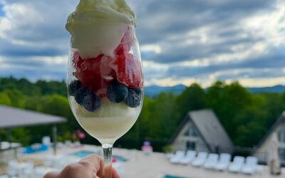 Dessert parfait with berries and whipped cream overlooking the outdoor pool and mountain scenery at SKYLARANNA Resort & Spa.
