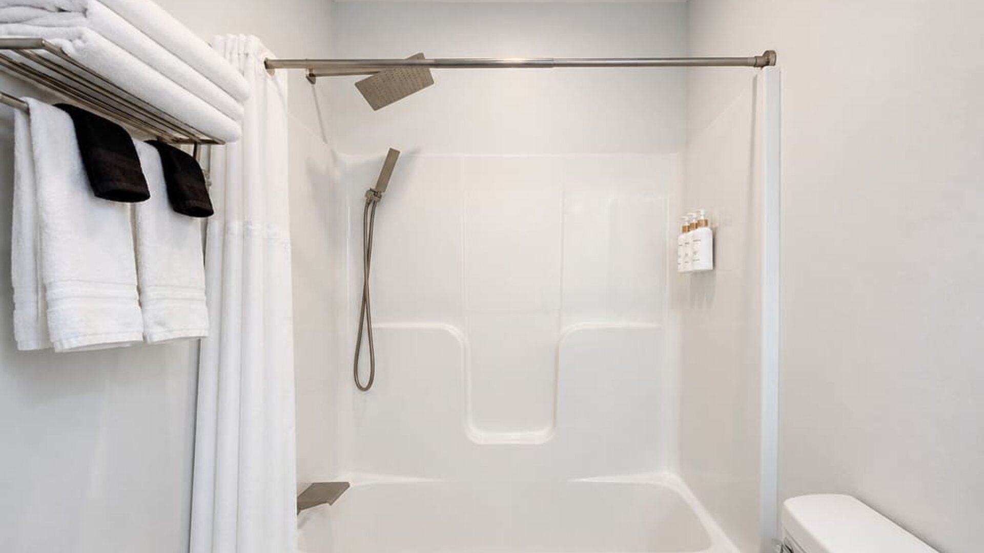 Guest bathroom featuring a bathtub and shower combination, modern shower fixtures, and neatly arranged towels at SKYLARANNA Resort & Spa.