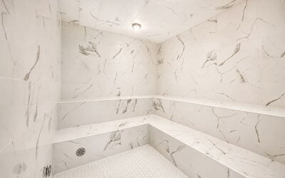 Steam room featuring marble-effect walls, built-in bench seating, and a bright contemporary interior at SKYLARANNA Resort & Spa.