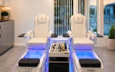 Spa area featuring two modern treatment chairs, foot basins, treatment products, and large windows at SKYLARANNA Resort & Spa.