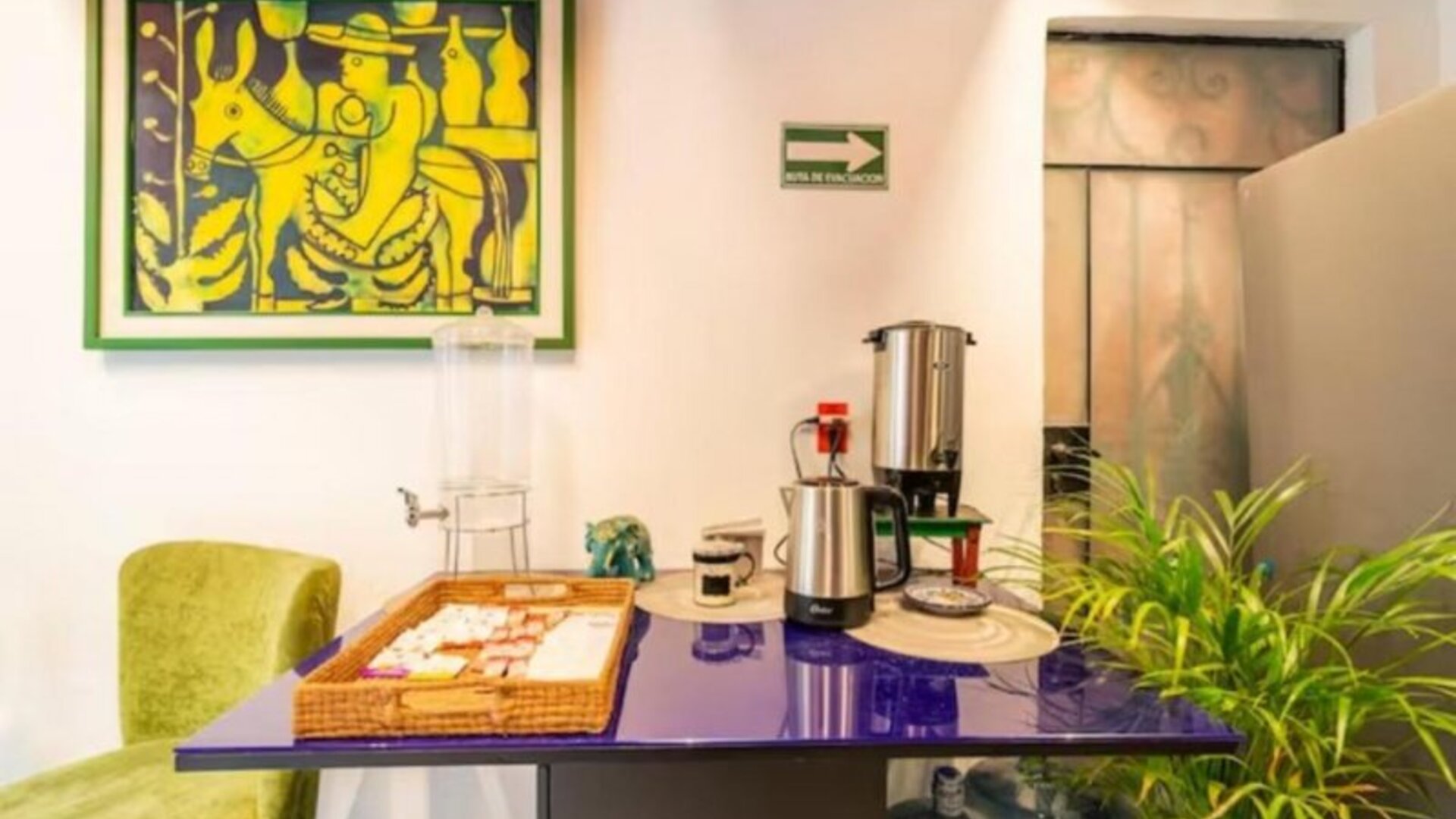 Guest refreshment station featuring coffee-making facilities, drinking water, snacks, and colourful artwork at Casa Anzures Suites.