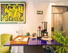 Guest refreshment station featuring coffee-making facilities, drinking water, snacks, and colourful artwork at Casa Anzures Suites.